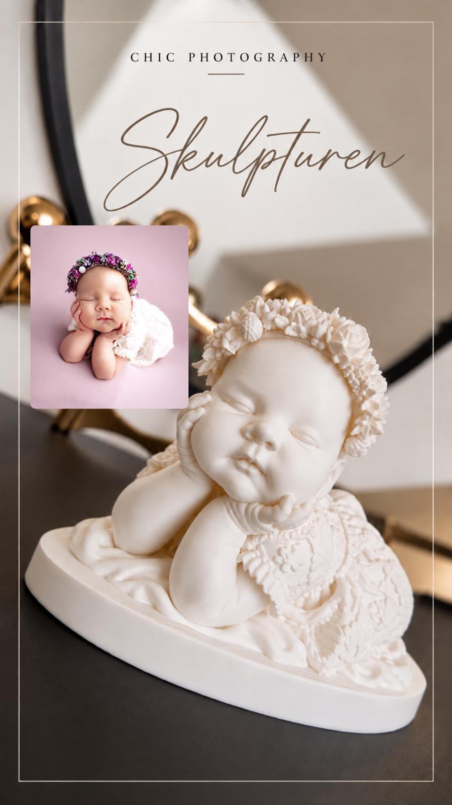 Neugeborenenfoto und passende Skulptur eines schlafenden Babys mit Blumenkranz